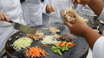 Close up of Evo EVent ventless griddle with matchstick carrots, sliced onions, pea pods, and steak being cooked on top