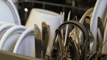 Close up of utensils and plates in a dishwasher