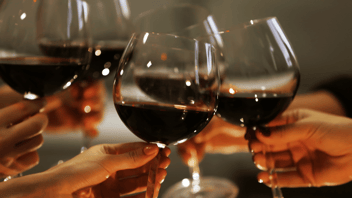 Four hands holding wine glasses filled with red wine