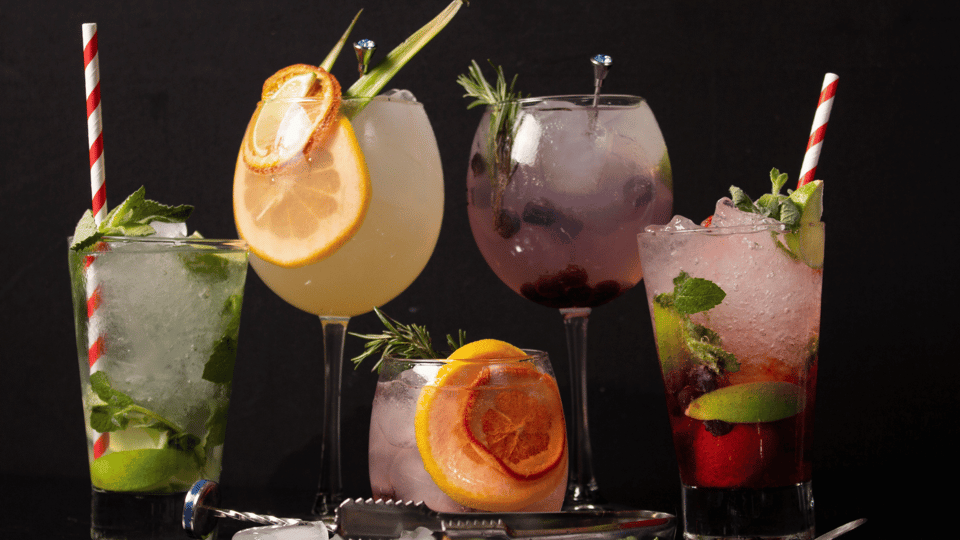 5 cocktails in different styles of glasses are on a black background
