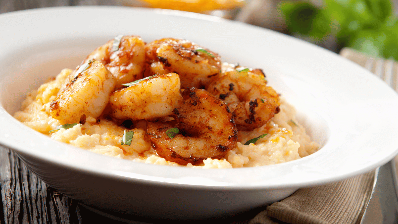 White bowl with creamy grils topped with sauteed shrimp